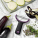 An OXO "Y" vegetable peeler with a wide stainless steel blade peeling an eggplant.