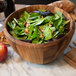 A Fox Run acacia wood salad bowl filled with salad and apples.
