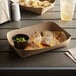 A Kraft paper food tray with quesadillas, tortillas, and guacamole on it.
