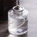 A clear glass jar of Sterno liquid candle fuel with a metal lid.