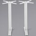 A pair of white BFM Seating Bali steel end table bases with circular designs on the legs.