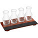 An Acopa flight tray with glass carafes of brown and red liquid on a table.