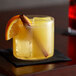 A glass of yellow liquid flavored with DaVinci Gourmet Classic Butterscotch Syrup with an orange slice and cinnamon stick.