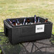 A Metro Mightylite food pan carrier with beer bottles in it on a table on a patio.