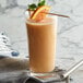 A glass of DaVinci Gourmet Classic Orange liquid with a straw and fruit on top.