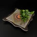 An Elite Global Solutions square melamine platter with green leaves on it.