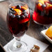 A glass of red liquid with fruit including orange slices.