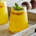 Two glasses of DaVinci Gourmet Passion Fruit Syrup in yellow liquid with mint leaves on top.