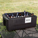 A Metro Mightylite food pan carrier with a blue lid filled with beer bottles on a table.