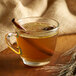 A glass cup of tea with DaVinci Gourmet Classic Butter Rum syrup and a cinnamon stick.