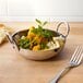 An American Metalcraft stainless steel balti bowl filled with rice and vegetables with a fork on the table.