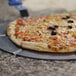 A close up of a pizza with olives and pepperoni on a GI Metal aluminum pizza tray with a polymer handle.