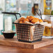 An Acopa black square mini fry basket filled with fried food on a table in a restaurant.