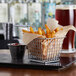 A rectangular mini fry basket filled with French fries and a glass of beer.
