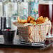 A chrome square mini fry basket filled with french fries and ketchup.
