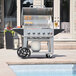 A Crown Verity mobile outdoor grill with a gas cylinder and a wind guard package on a cart.