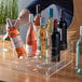 A hand using a Choice 3 Tier Syrup Bottle Organizer to hold a bottle of wine.