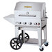A stainless steel Crown Verity mobile outdoor barbecue grill with wheels and a lid.