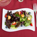 A Fineline white plastic salad plate with a salad of strawberries and blueberries.