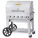 A silver stainless steel Crown Verity mobile outdoor grill with wheels and knobs.