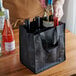 A person putting bottles of wine in a black Franmara reusable bag.