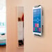 A silver metal Durable wall-mounted tablet holder with a smart phone connected to it.