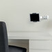 A Durable silver metal wall-mount tablet holder with a swinging arm holding a tablet on a wall.