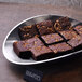 A Bon Chef stainless steel petalo angled platter with a plate of brownies on it.