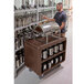 A man standing next to a Cambro dark brown service cart full of silverware.