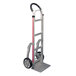 A silver and black Magliner hand truck with red handle and rubber wheels.