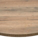 A BFM Seating Relic Knotty Pine round melamine table top with matching edge on a table.