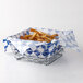An American Metalcraft chrome square birdnest basket filled with french fries on a table.