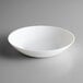 An Arcoroc white opal glass soup plate on a gray surface.