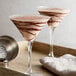 A pair of martini glasses with chocolate and vanilla drinks in them.