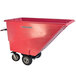 A red cart with wheels with dual handle bars and a motorized hopper.