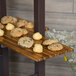 A Cal-Mil crushed bamboo shelf holding a tray of cookies on a wood surface.