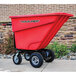 A red Magliner motorized hopper cart with dual handle bars on a sidewalk.