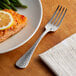 A plate of salmon with a lemon slice on top and an Acopa Industry stainless steel dinner fork.