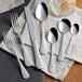 A group of Acopa stainless steel teaspoons on a table with a napkin