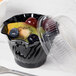 A black plastic Cambro swirl bowl with fruit inside.