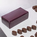 A maroon candy box on a white surface.
