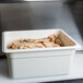 A white Cambro plastic food pan filled with food.