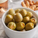 A bowl of Belosa blue cheese and habanero pepper stuffed green olives on a table in a deli.