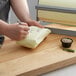 A person cutting Gardenia Premium Butcher Paper with a knife.