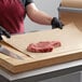 A person using Choice natural kraft freezer paper to wrap meat on a cutting board.