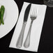 A knife and fork on a white Hoffmaster Quickset linen-like dinner napkin.