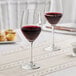 A pair of Acopa wine glasses on a table with a glass of red wine.