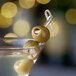 A close-up of a martini glass with Belosa blue cheese stuffed queen olives in it.