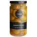A jar of Belosa hickory-smoked almond stuffed queen olives with a black label on a table.