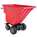 A red self dumping hopper with wheels and dual handle bars.